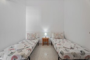 Ein Doppelzimmer mit zwei Einzelbetten, einem Nachttisch mit Lampe und einem kleinen Tisch.