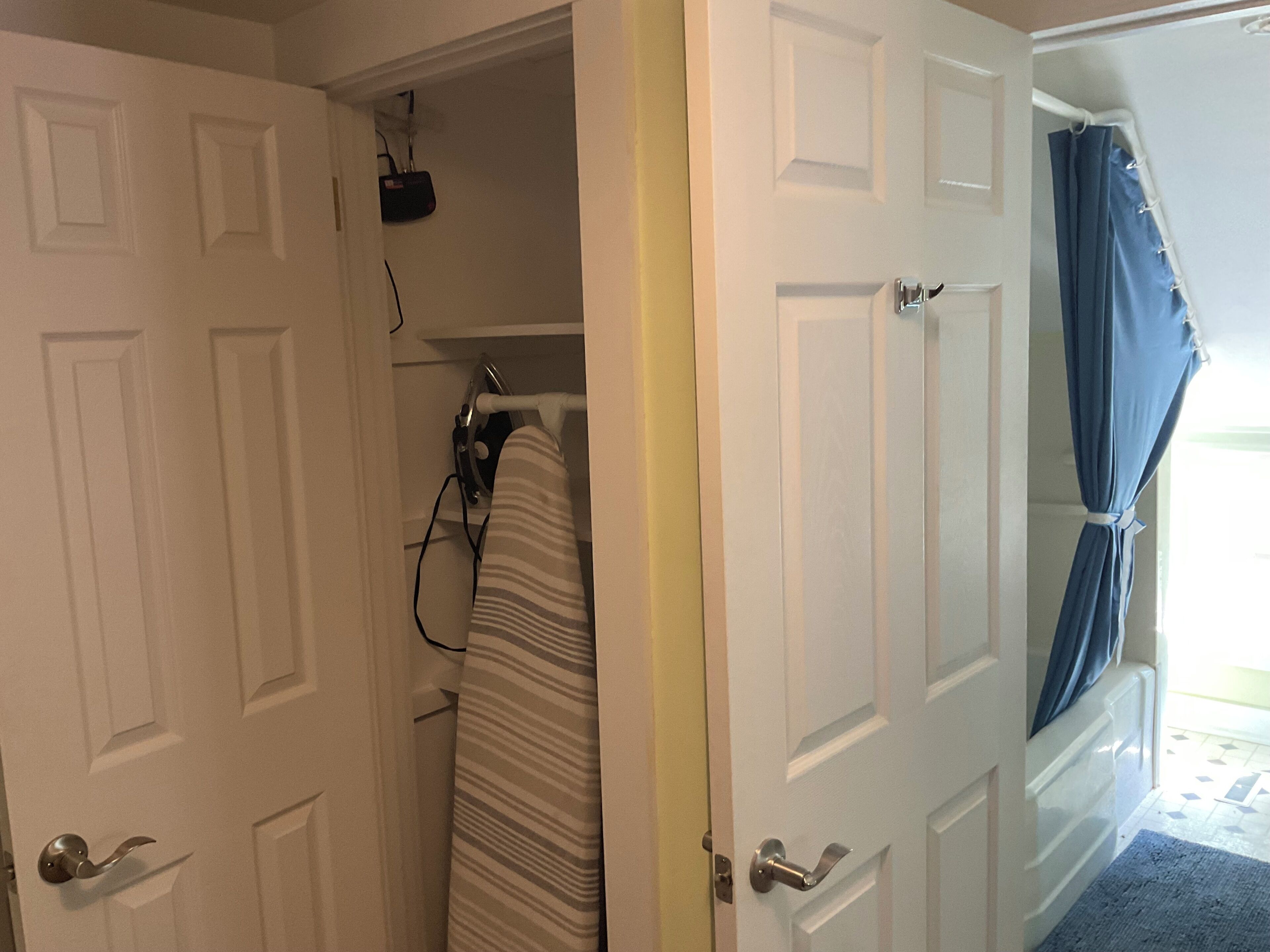 Um quarto com porta fechada, área de chuveiro com cortina e uma tomada visível.