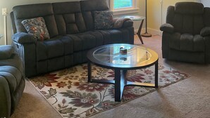 A living room with a sofa, armchair, and a glass coffee table. -  3-bedroom country home in  Greenfield Ctr. NY. Central HVAC 15min to Saratoga. (Greenfield Center)