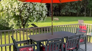 A deck with a table and chairs, an umbrella, and a garden with trees and flowers. -  3-bedroom country home in  Greenfield Ctr. NY. Central HVAC 15min to Saratoga. (Greenfield Center)