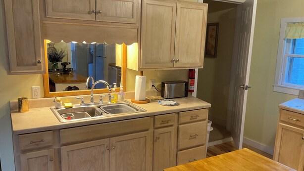 A kitchen with a double sink, a toaster, and wooden cabinets. -  3-bedroom country home in  Greenfield Ctr. NY. Central HVAC 15min to Saratoga. (Greenfield Center)