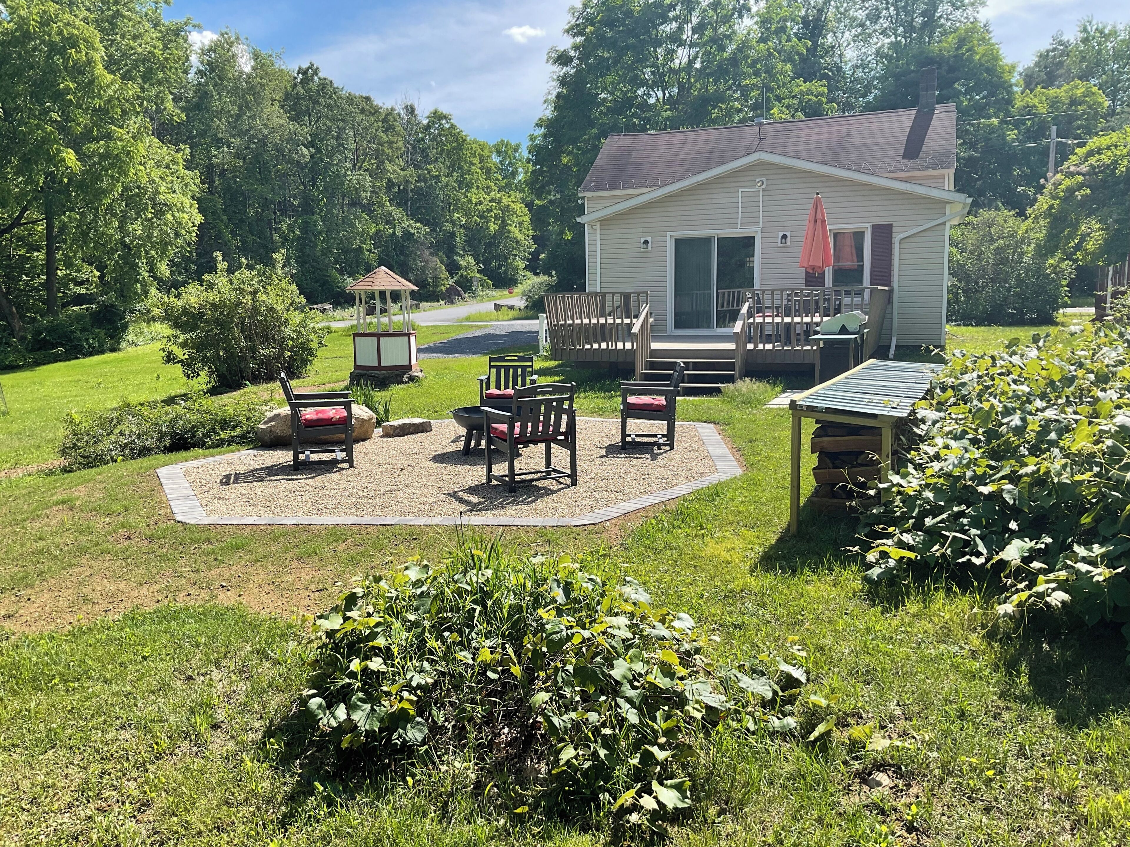 A small house with a deck, outdoor seating, and a garden.