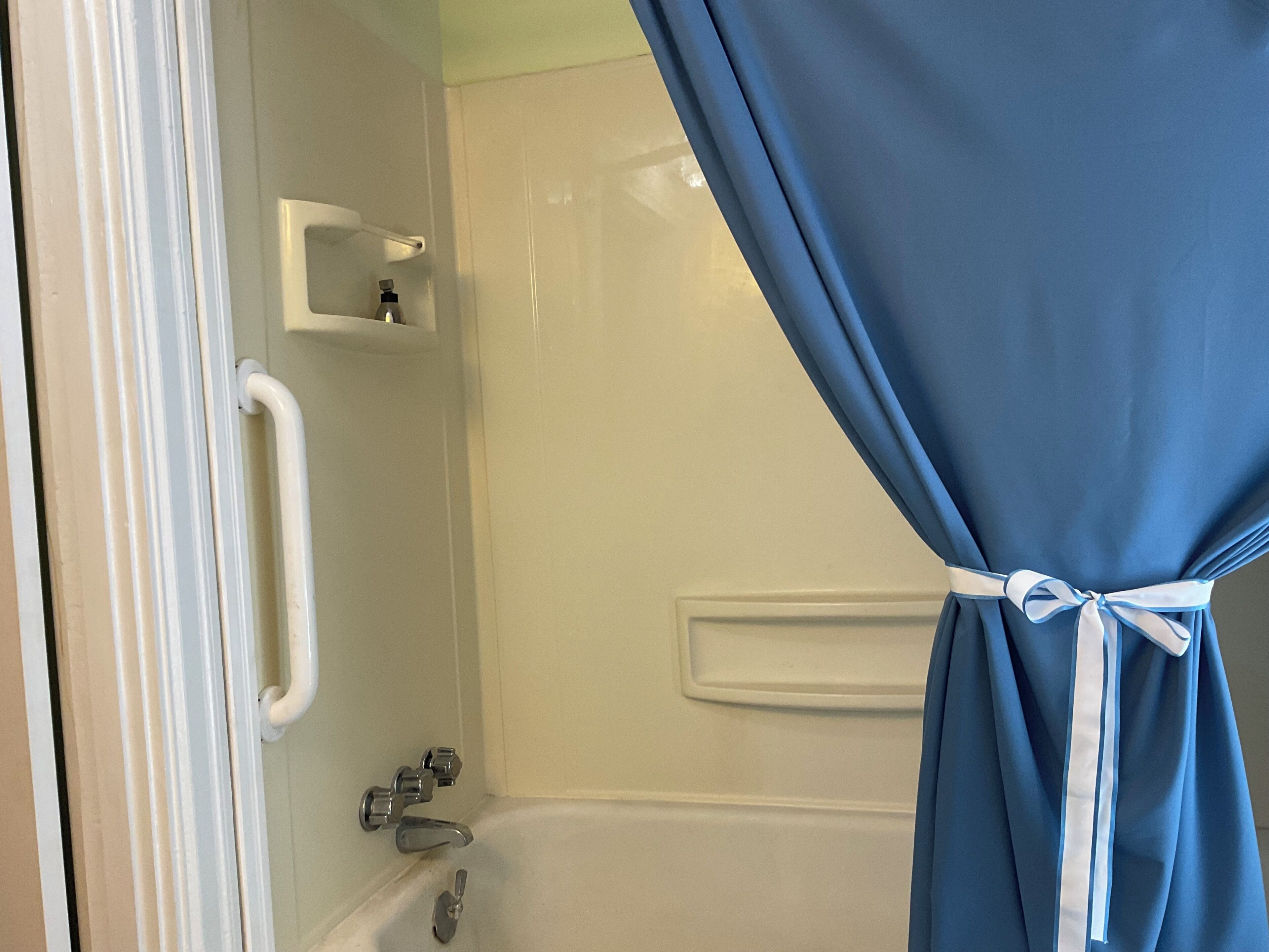A bathroom with a bathtub, a shower, and a towel rack.