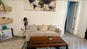 Un salon avec un canapé, une table basse, une carte du monde accrochée au mur et un tapis à motifs.