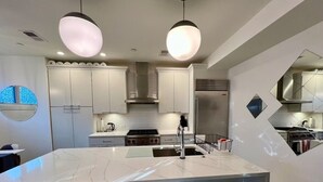 Une cuisine moderne dotée d’un îlot central, d’appareils électroménagers en acier inoxydable et d’un coin repas avec des tabourets de bar.
