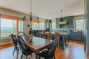 Una cocina moderna con una mesa de comedor de madera, sillas negras y vistas al exterior.