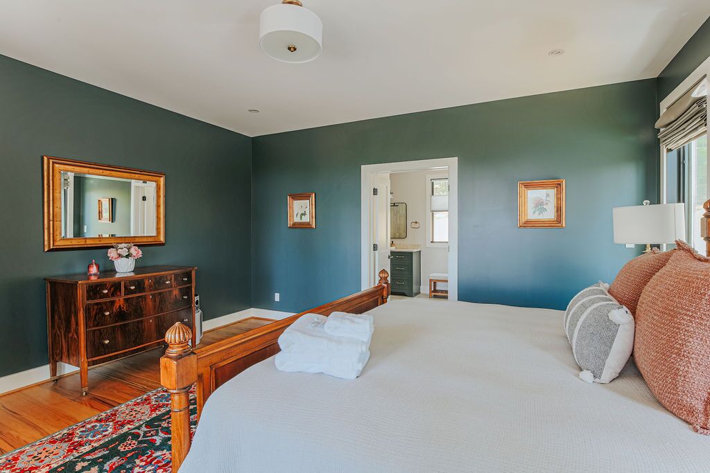A bedroom with a large bed, wooden headboard, a dresser, and a mirror on the wall.