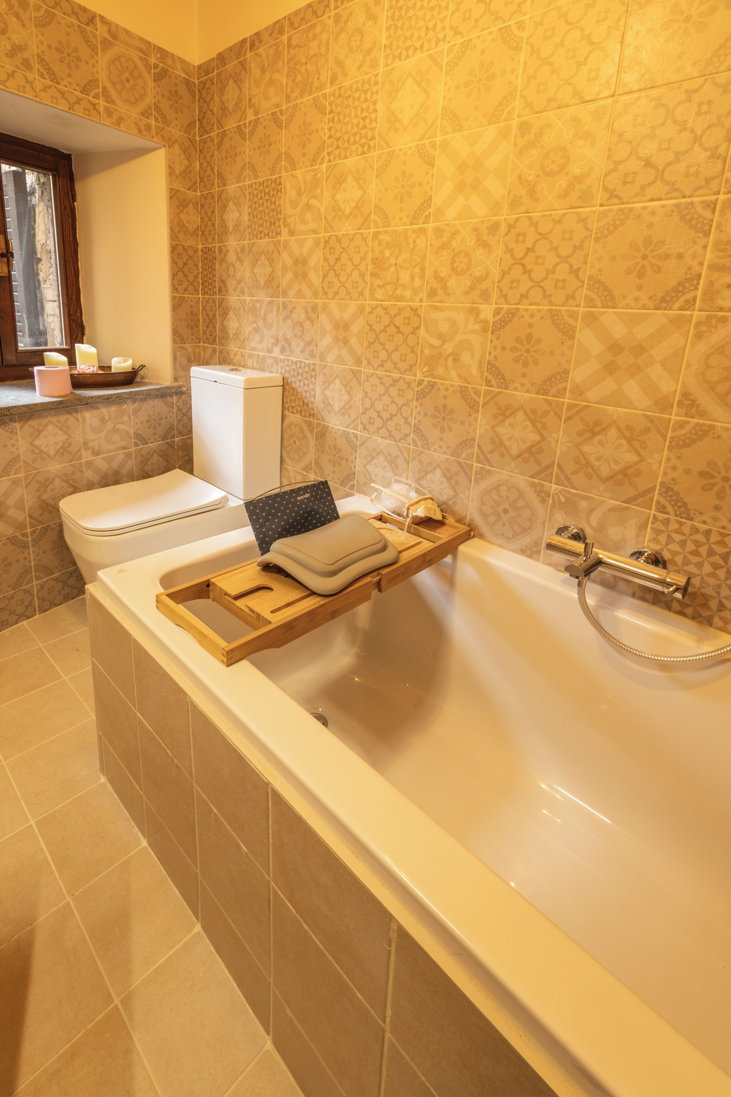 Une salle de bain équipée d’une baignoire, de toilettes et d’une étagère où sont rangés les articles de toilette.