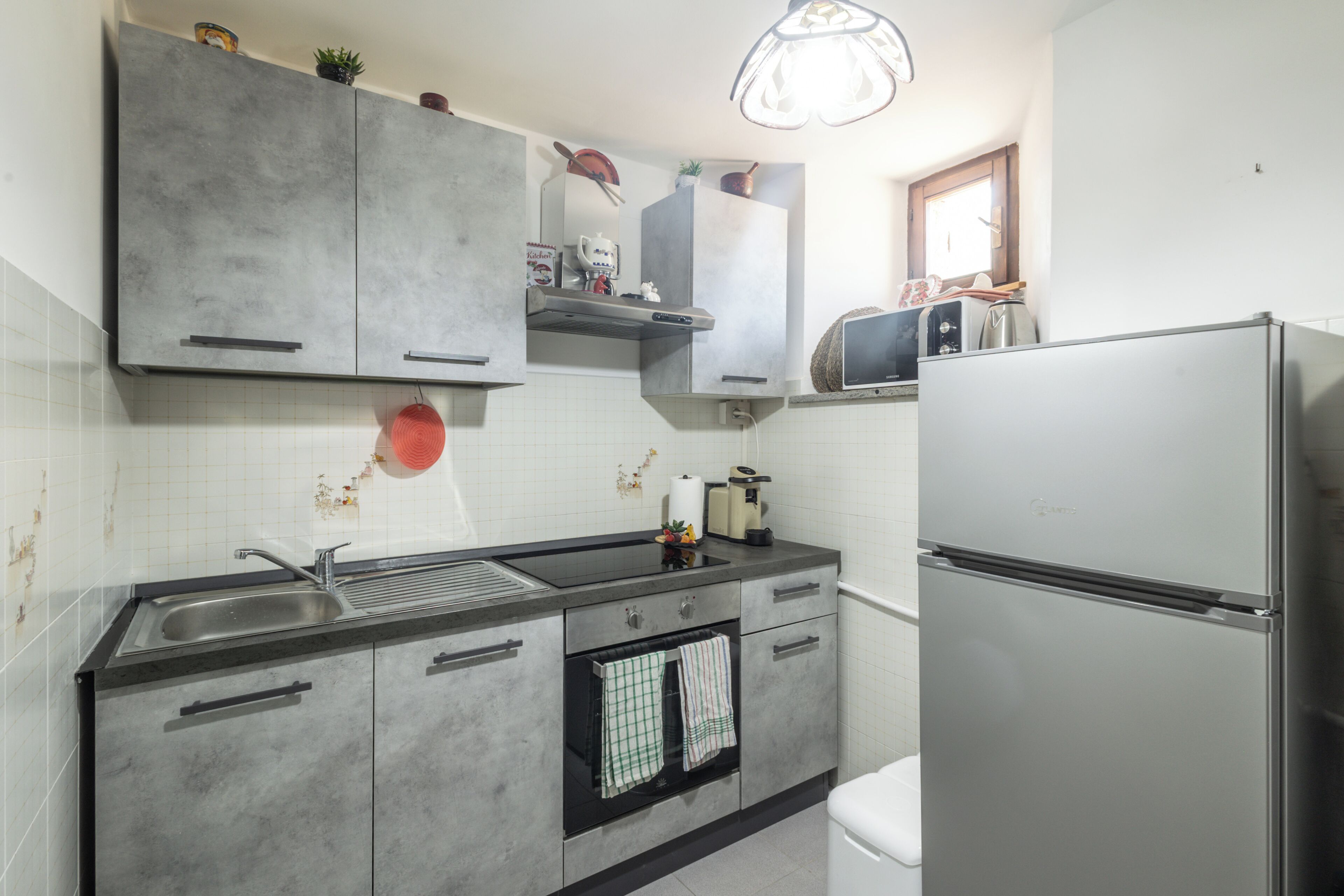 Eine Küche mit einem Edelstahl-Kühlschrank, einer Spüle mit zwei Becken und einem eingebauten Backofen.