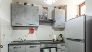 Una cocina con armarios grises, un refrigerador de acero inoxidable, una lámpara colgante y un protector de salpicadero de azulejos.