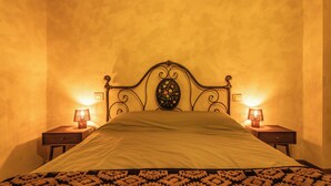 Una cama con cabecera, dos mesitas de noche con lámparas y una colcha estampada.