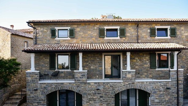 A stone building with two balconies, arched doorways, and a tiled roof. - Platano, ADQ (Buje)