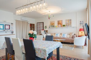 Ein modernes Wohnzimmer mit Essbereich, einer Kronleuchter und Kunstwerken an den Wänden.