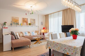 Ein modernes Wohnzimmer mit einer Couch, einem Couchtisch, einem Fernseher und einem Essbereich mit Tisch und Stühlen.