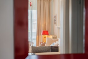 Ein Hotelzimmer mit Bett, Nachttisch mit Lampe, Stuhl und einem Fenster mit Vorhängen.