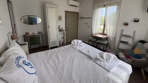 A hotel room with a bed, a desk, a chair, a wardrobe, a mirror, and a window with curtains.