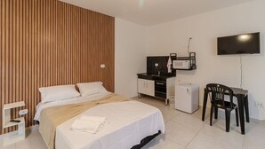 A hotel room with a bed, a desk, a TV, a microwave, and a small refrigerator. - Studio 12 com Wi-fi e Pr Ximo ao Shopping Tatuap (São Paulo)