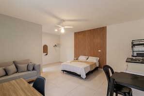 Um quarto moderno com cama, sofá, mesa de jantar e ventilador de teto.