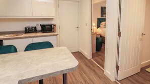 A compact kitchen with a microwave, a small table, and teal chairs. - Hidden Gem (Windermere)