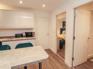 A compact kitchen with a microwave, a small table, and teal chairs. - Hidden Gem (Windermere)