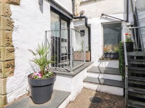 Ein kleiner Außenbereich mit einem Blumentopf, einem Metallgeländer und Stufen, die zu einer Tür führen.
