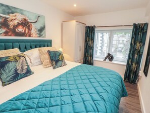 A bedroom with a large bed, a headboard, a window with curtains, and a painting on the wall. - Hidden Gem (Windermere)