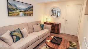 A living room with a sofa, a coffee table, a painting, a mirror, and a door. - Hidden Gem (Windermere)