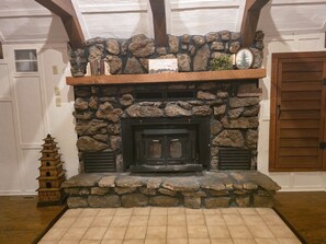 A stone fireplace with a wooden mantel, a small wooden ladder, and a framed picture.
