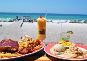 Ein Tisch mit Speisen und Getränken an einem Strand, im Hintergrund der Ozean.