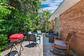 Un patio al aire libre con una parrilla, muebles de mimbre y un muro de ladrillo.