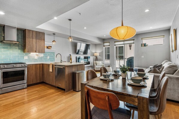 A modern kitchen with wooden cabinets, a built-in oven, and a dining area with a wooden table and chairs. - Large & Luxury Modern Townhome in Tennyson Berkley (Denver)
