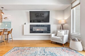 A modern living room with a fireplace, a dining area with wooden chairs, and a large rug. - Large & Luxury Modern Townhome in Tennyson Berkley (Denver)