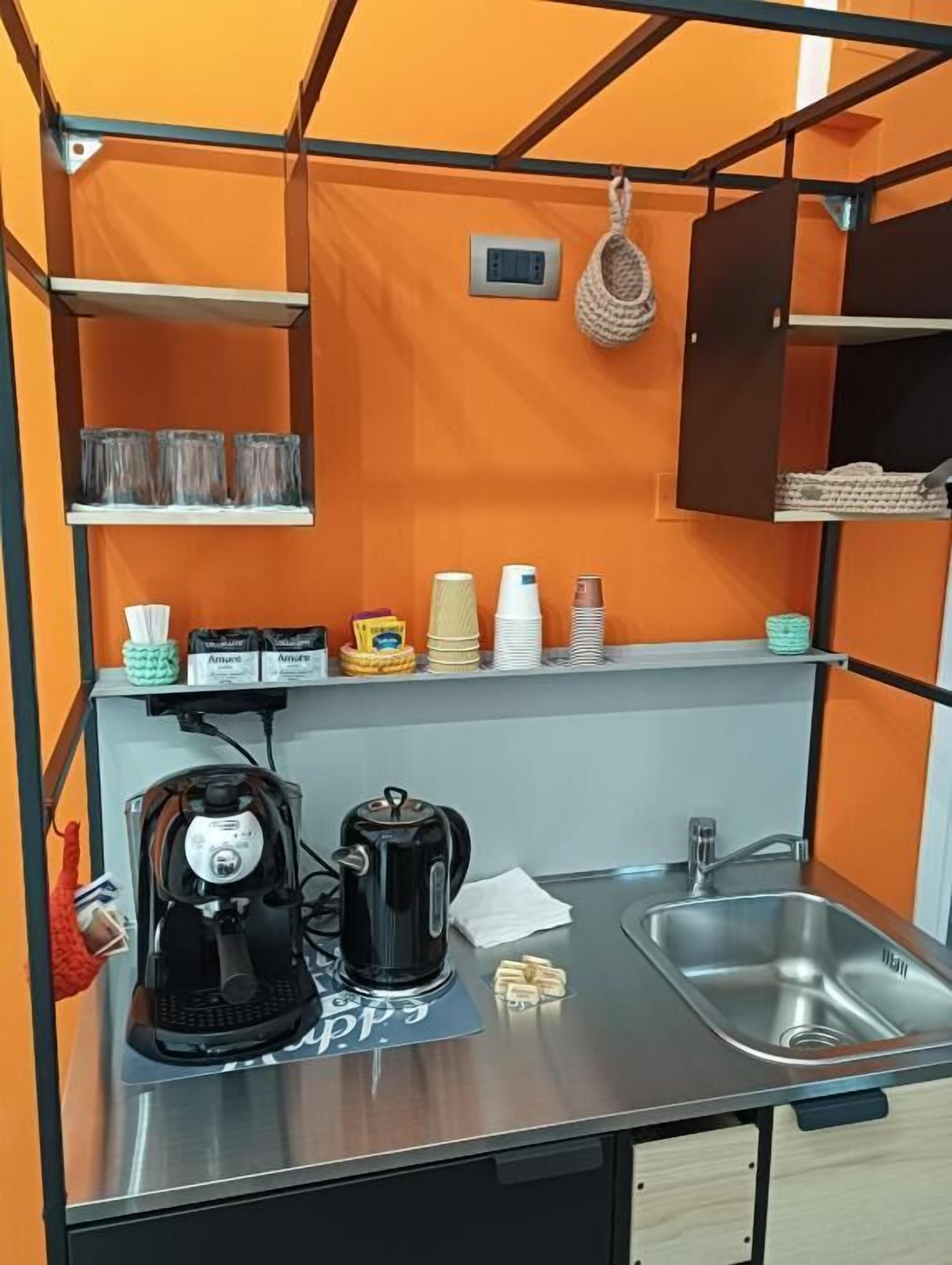 Een kleine keuken met een koffiezetapparaat, waterkoker en spoelbak.