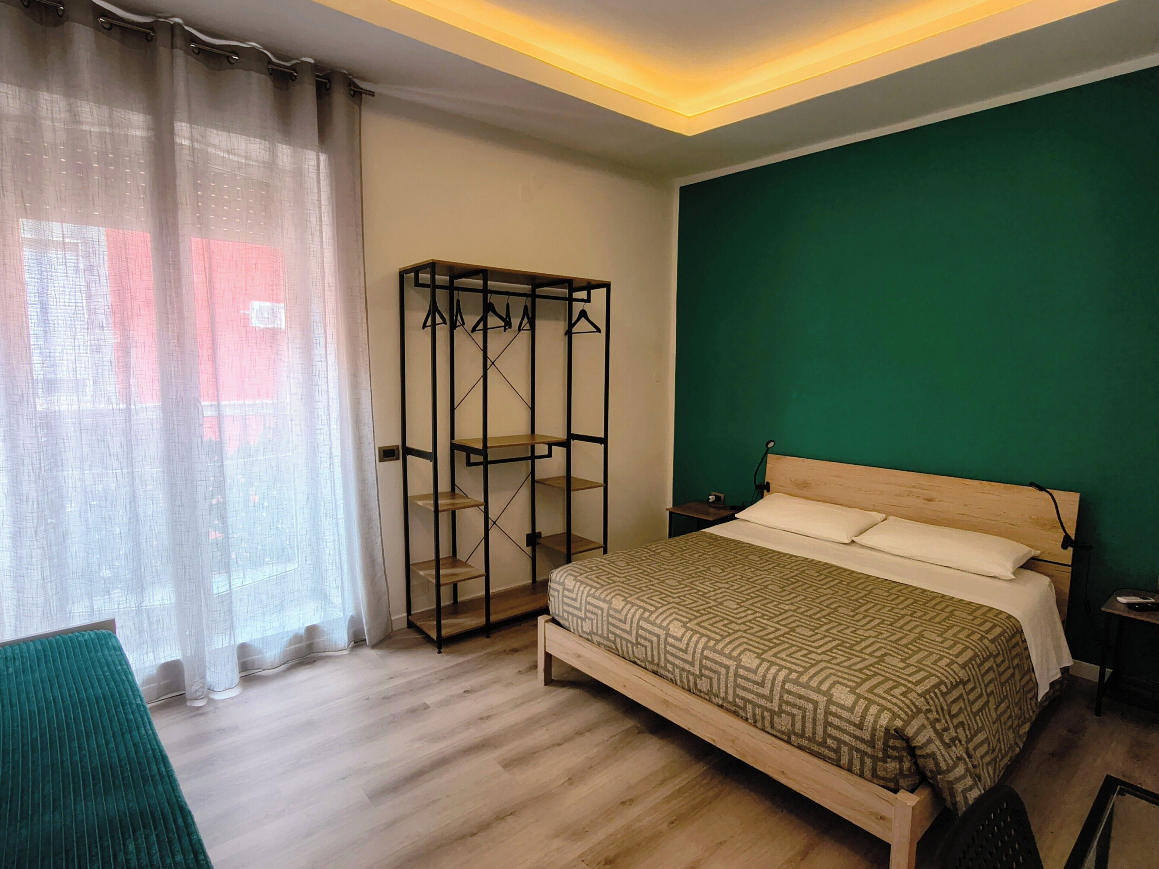 Un dormitorio con cama, armario y pared verde.