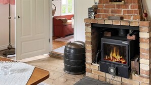 A room with a brick fireplace, a wooden table, and a red sofa. - 3 Person Holiday Home in Fjardhundra (Fjärdhundra)