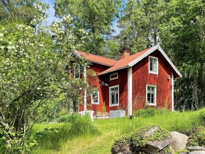 A red wooden house surrounded by greenery. - 3 Person Holiday Home in Fjardhundra (Fjärdhundra)