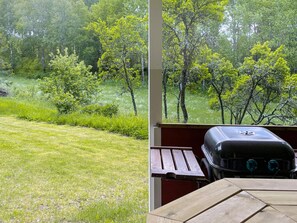 Vista de un área verde con árboles y una parrilla de barbacoa sobre una mesa de madera.