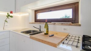 Een moderne keuken met een houten aanrecht, een wijnfles, een spoelbak en een raam boven het aanrecht.
