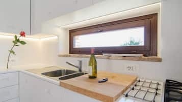 Una cucina moderna con un piano di lavoro in legno, una bottiglia di vino, un lavello e una finestra sopra il piano.
