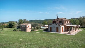 Een villa met een gevel van natuursteen, een overdekt terras en uitzicht op het omliggende landschap.