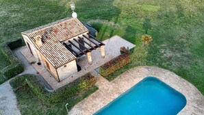 Zona de piscina amb una pèrgola, un edifici petit i una piscina.