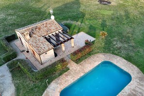 Zona junto a la piscina con una pérgola, un edificio pequeño y una pileta.