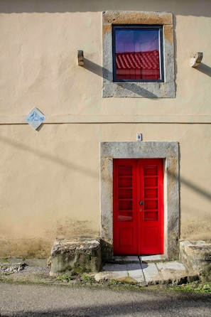 Un edificio con una puerta roja y una ventana que da a tejados rojos.