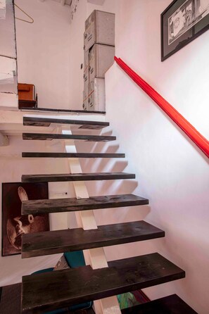 Una escalera con escalones negros y barandilla roja.
