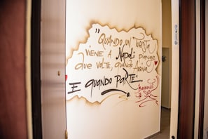 A wall with handwritten text in a foreign language, a door, and a hallway. - Holiday Home "Solemare Musica & Poesia" (napoli)