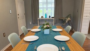 Een eettafel gedekt met borden, bestek en een vaas met bloemen.