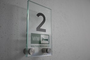 A glass wall sign with the number 2, indicating room number, a bed icon, and the name 'WALTERS WEIDELBACH' below. - Walters Weidelbach House in Haiger, Lahn-Dill District (Haiger)