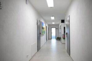 A hallway with white walls, a tiled floor, and doors on both sides. There is a fire extinguisher mounted on the wall. - Walters Weidelbach House in Haiger, Lahn-Dill District (Haiger)