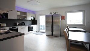 Eine moderne Küche mit weißen Schränken, einem Side-by-Side-Kühlschrank und einem Essbereich mit Tisch und Stühlen.