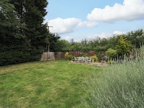 Ein Garten mit Holzzaun, Terrassentisch und Stühlen sowie verschiedenen Pflanzen.